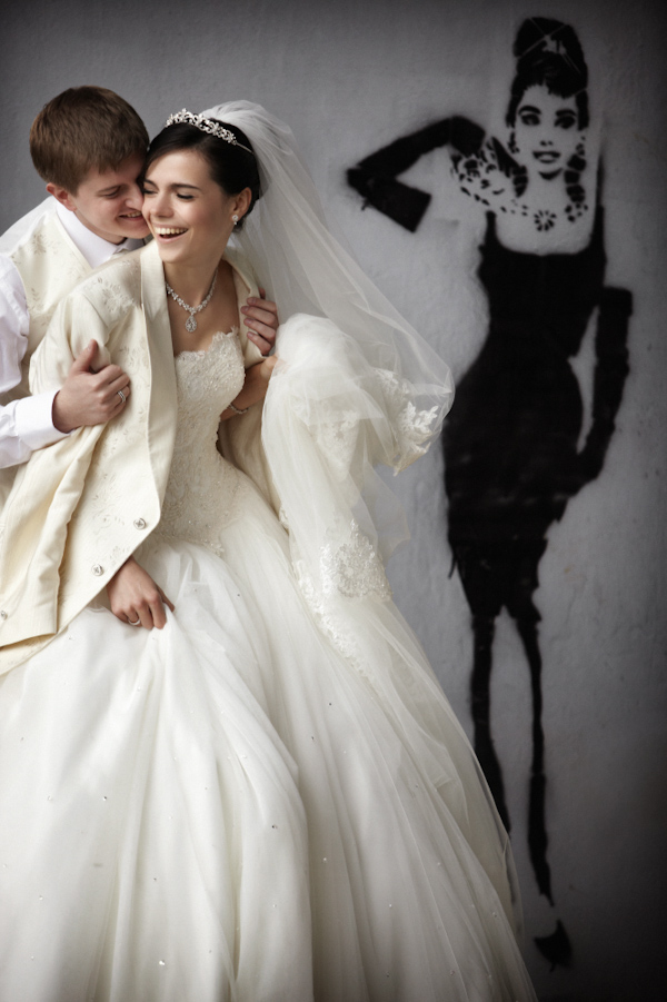 gorgeous ivory embellished ballgown style wedding dress, happy couple portrait in front of audrey hepburn graffiti art - photo by destination wedding photographer Jerry Ghionis